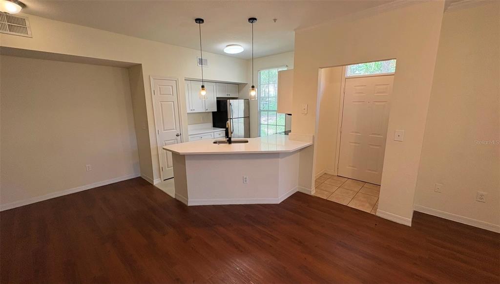 An open-concept kitchen features white cabinets, a breakfast bar, and wood-look flooring — 6348 RALEIGH STREET UNIT 1304, ORLANDO, FL