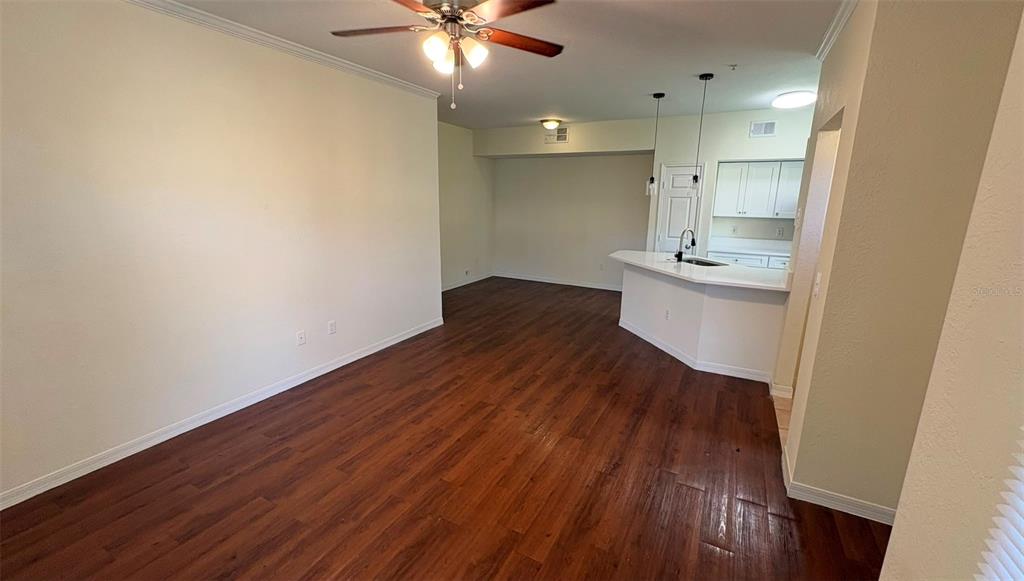 An open-concept living and dining area features dark wood-look flooring and a kitchen breakfast bar — 6348 RALEIGH STREET UNIT 1304, ORLANDO, FL