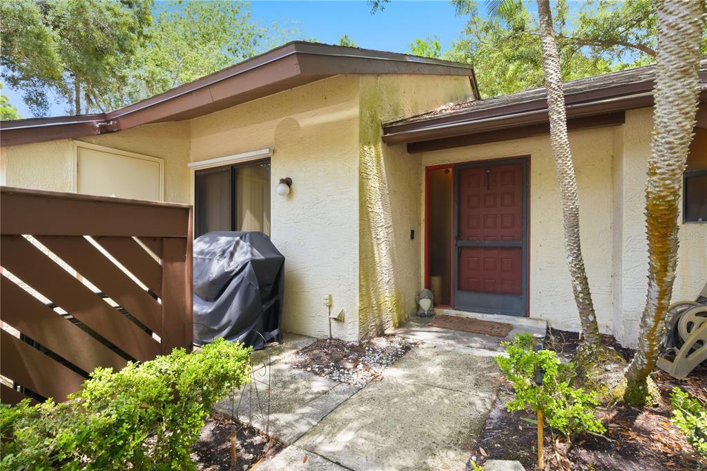 The exterior of a house features a covered entryway, a red door, and a grill — 4041 ARROWWOOD COURT UNIT 4041, PALM HARBOR, FL