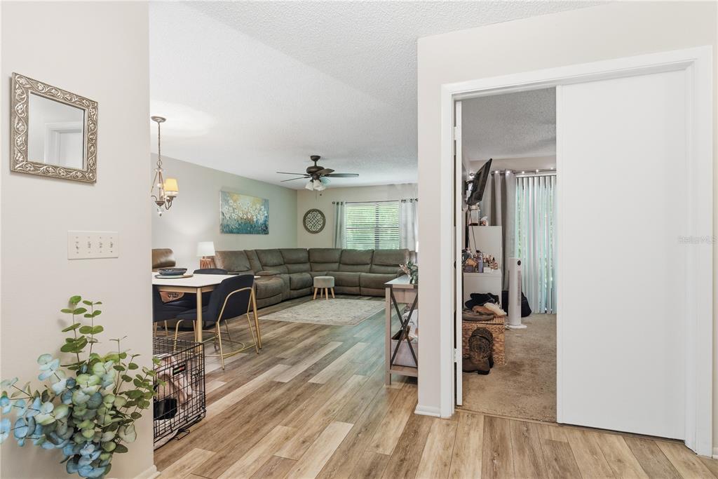 An open-concept living and dining area features wood-look flooring and a large sectional sofa — 4041 ARROWWOOD COURT UNIT 4041, PALM HARBOR, FL