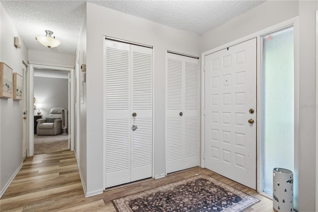 An entryway features a white front door, two louvered closet doors, and wood-look flooring — 4041 ARROWWOOD COURT UNIT 4041, PALM HARBOR, FL