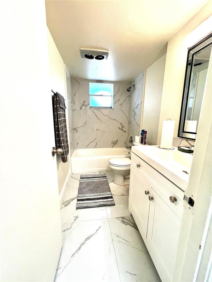 A bathroom features white marble-look tile flooring and shower walls, a vanity, and a tub — 3080 Holiday Springs Boulevard # 301, Margate FL 33063, MARGATE, FL