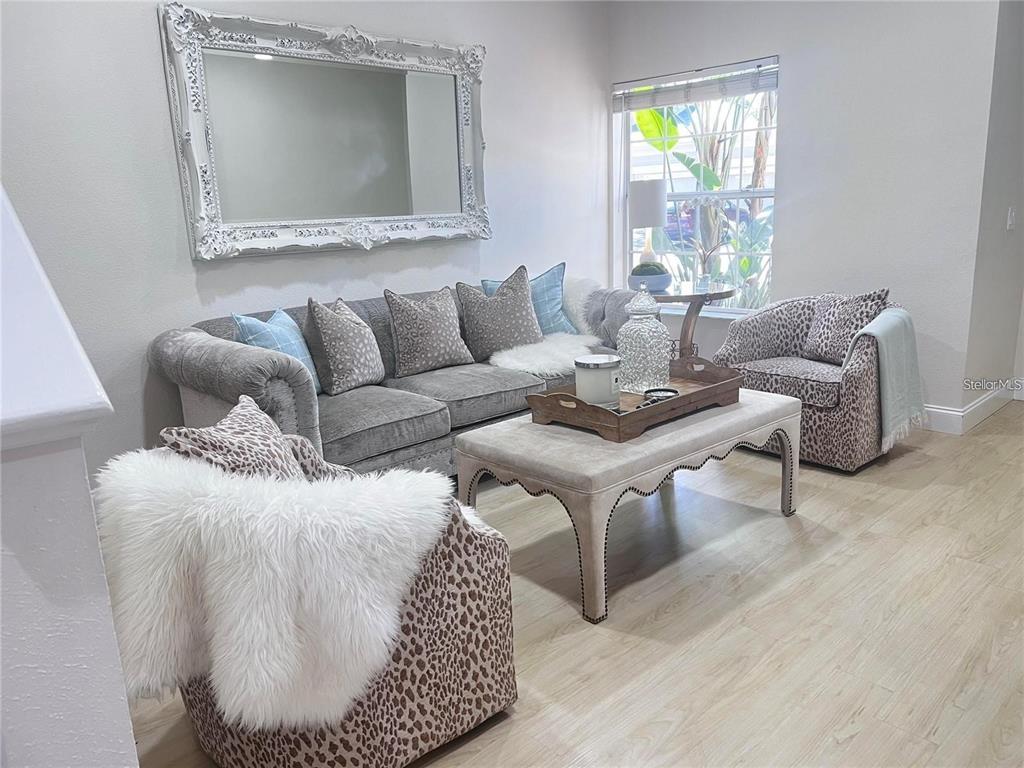 A living room features a grey sofa, two leopard-print chairs, and a large ornate mirror — 7658 PLANTATION CIRCLE, BRADENTON, FL