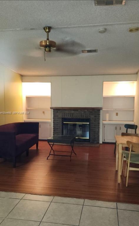 A living room features a brick fireplace, built-in shelving, wood flooring, and a ceiling fan — 1233 SW 130 Ave # 1233, Miami FL 33184, MIAMI, FL