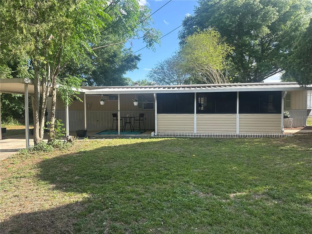 A mobile home exterior features a covered patio, screened-in porch, and a metal roof — 10448 SE 148TH PLACE, SUMMERFIELD, FL