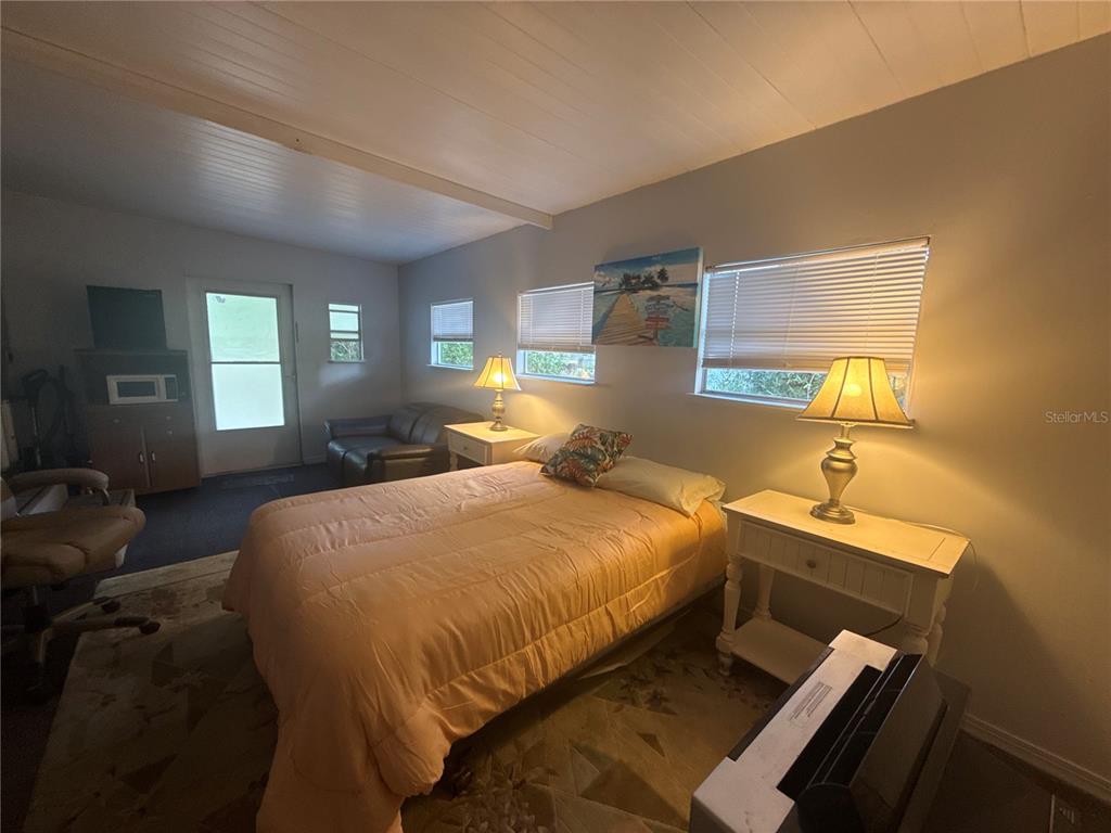 A bedroom features a bed with an orange comforter, two nightstands with lamps, and windows — 10448 SE 148TH PLACE, SUMMERFIELD, FL