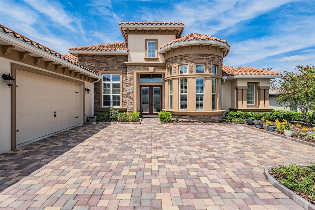 A single-story house with a stone facade, tile roof, and a paved driveway — 13915 CARRYBACK DRIVE, DADE CITY, FL