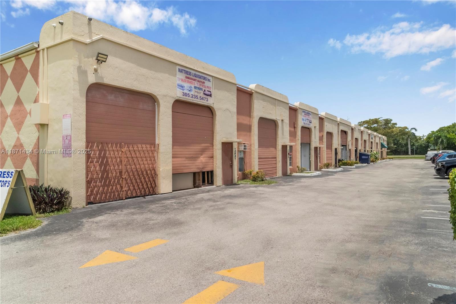 A row of commercial warehouse units with roll-up doors and a paved parking lot — 12300 SW 117 CT, FL 33186, FL