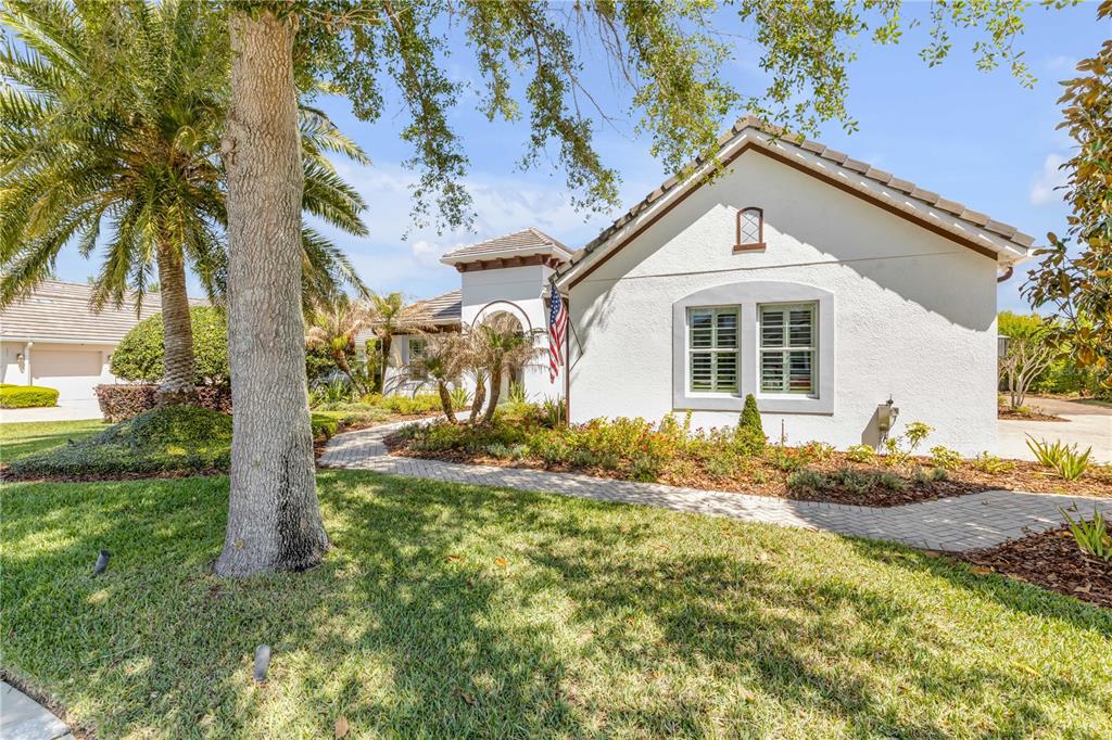 A white stucco house with a tiled roof features a brick walkway and palm trees — 3029 ISOLA BELLA BOULEVARD, MOUNT DORA, FL