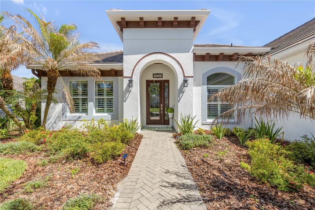 A single-story house exterior features a paved walkway leading to an arched front entryway — 3029 ISOLA BELLA BOULEVARD, MOUNT DORA, FL