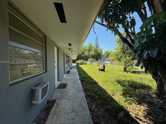 A concrete walkway runs along the exterior of a gray building with a window unit — 151 NW 164th ST, Miami FL 33169, MIAMI, FL