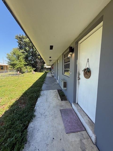 A concrete walkway runs along the exterior of a building with a white door — 151 NW 164th ST, Miami FL 33169, MIAMI, FL