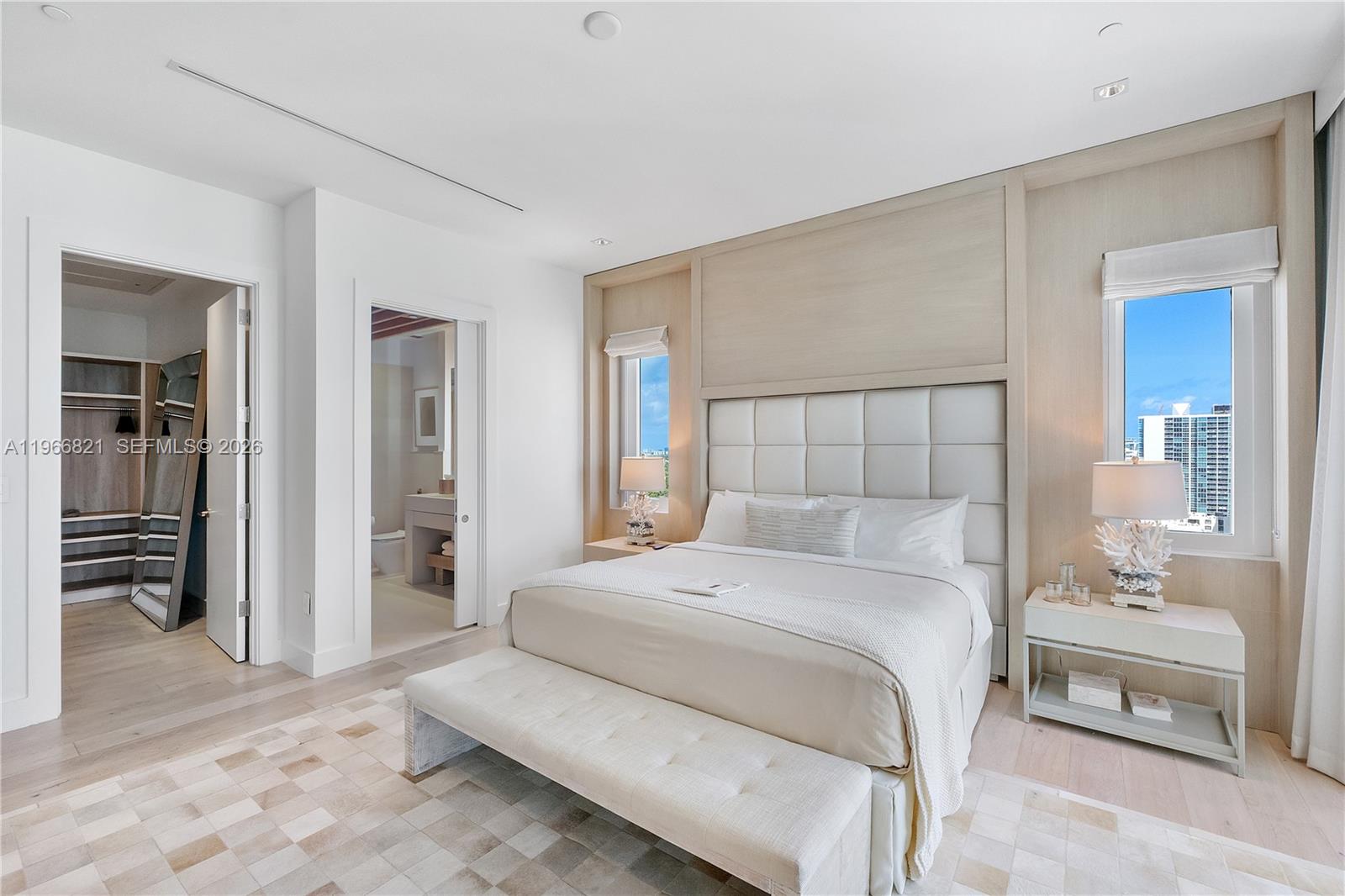 A modern bedroom features a tufted headboard, two windows, a bench, and an attached closet — 102 24th St # 1612, Miami Beach FL 33139, MIAMI BEACH, FL