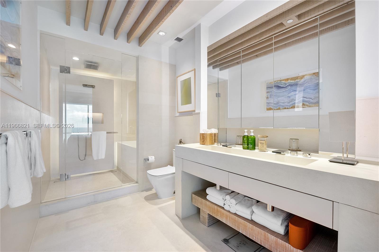 A modern bathroom features a glass-enclosed shower, a floating vanity, and wooden ceiling beams — 102 24th St # 1612, Miami Beach FL 33139, MIAMI BEACH, FL
