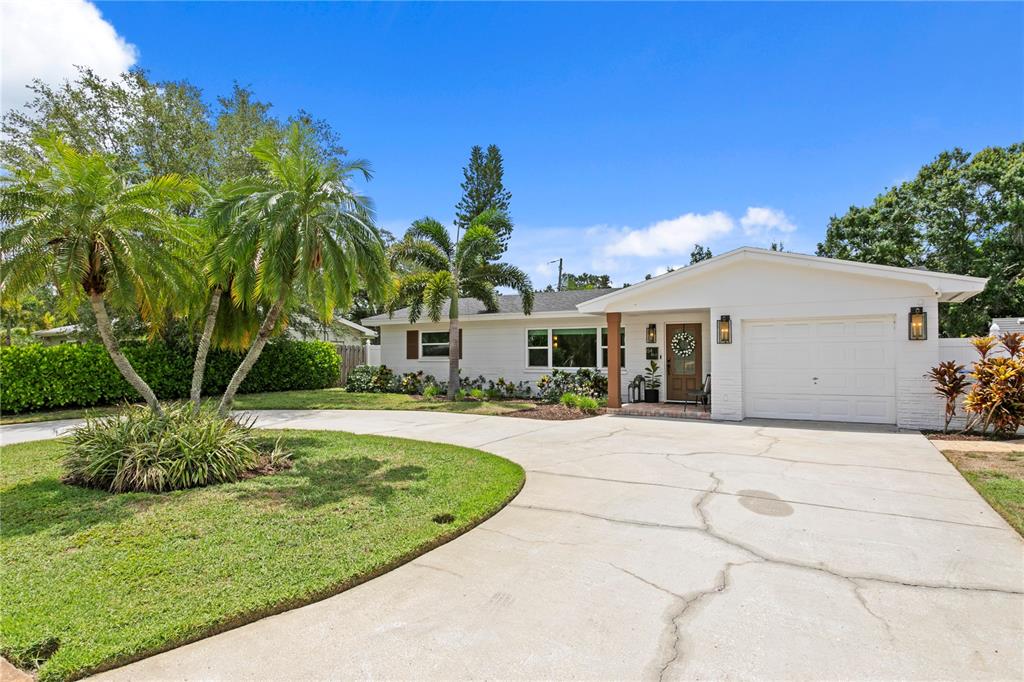 A single-story white house with a palm tree, a circular driveway, and a garage — 154 45TH AVENUE NE, ST PETERSBURG, FL