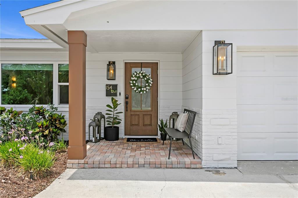 The exterior of a house features a brown front door, a brick porch, and a bench — 154 45TH AVENUE NE, ST PETERSBURG, FL