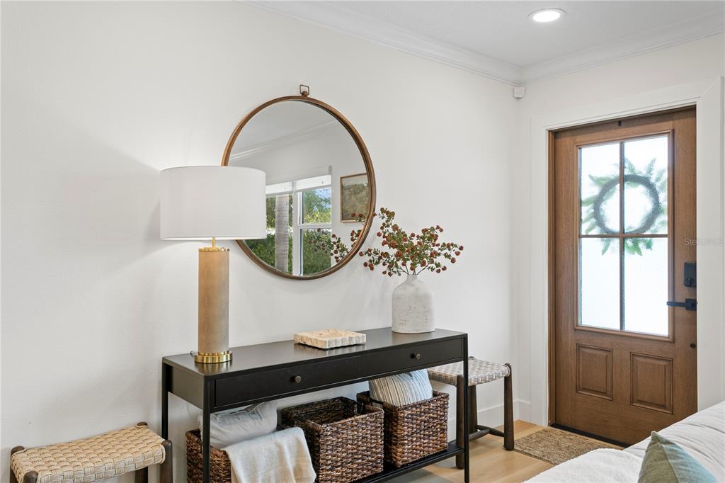 An entryway features a black console table, a round mirror, and a wooden front door — 154 45TH AVENUE NE, ST PETERSBURG, FL
