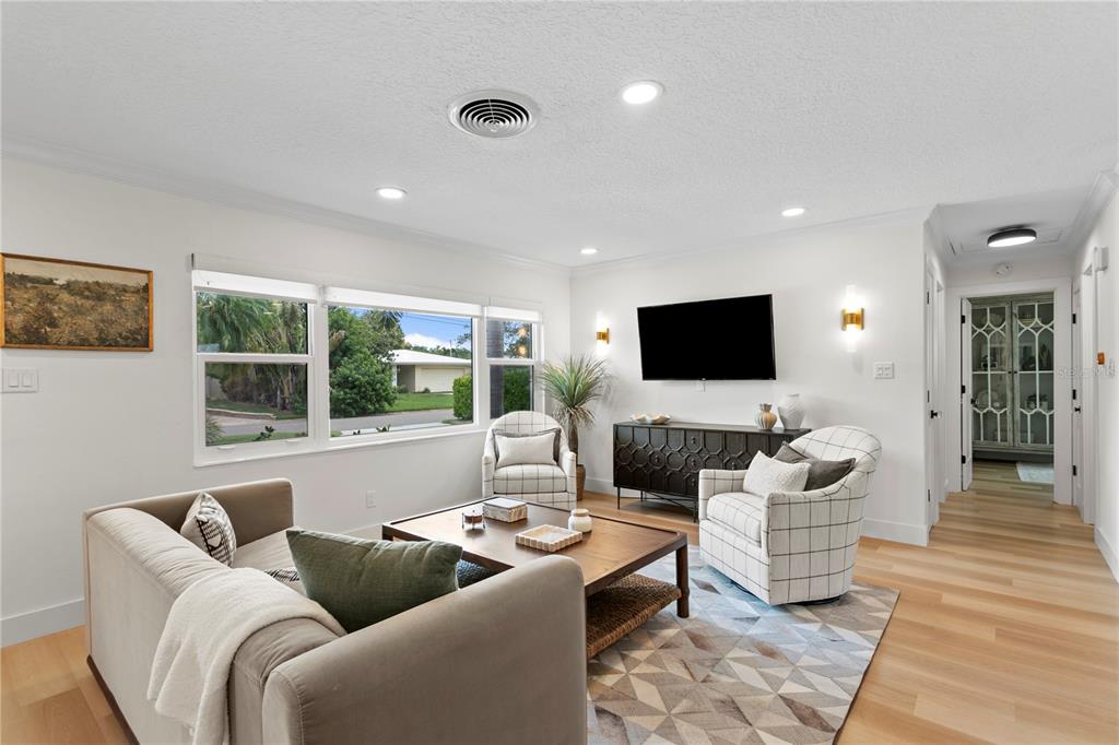 A living room features a beige sofa, two plaid armchairs, a wooden coffee table, and a television — 154 45TH AVENUE NE, ST PETERSBURG, FL