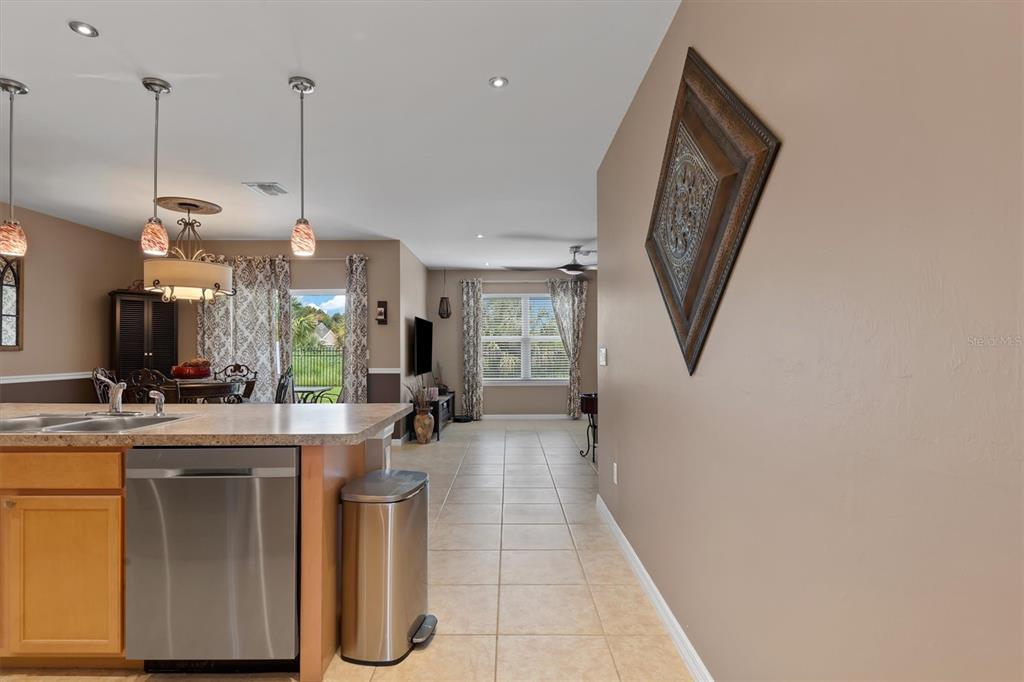 A kitchen island with a stainless steel dishwasher overlooks an open-concept living and dining area — 7436 MIKASA DRIVE, PUNTA GORDA, FL