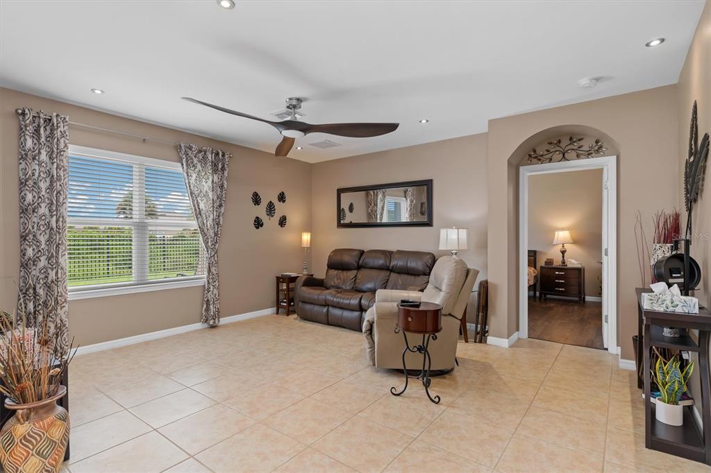 A living room with tile flooring, a brown leather sofa, and a ceiling fan — 7436 MIKASA DRIVE, PUNTA GORDA, FL