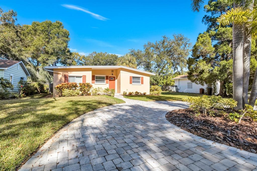 A single-story house with a paved driveway, tan exterior, and a detached garage — 5813 27TH AVENUE S, GULFPORT, FL