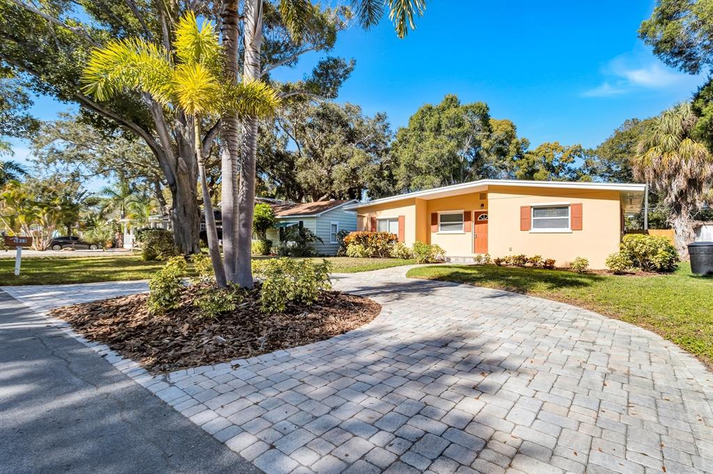 A yellow single-story house features a paved driveway, a palm tree, and landscaping — 5813 27TH AVENUE S, GULFPORT, FL