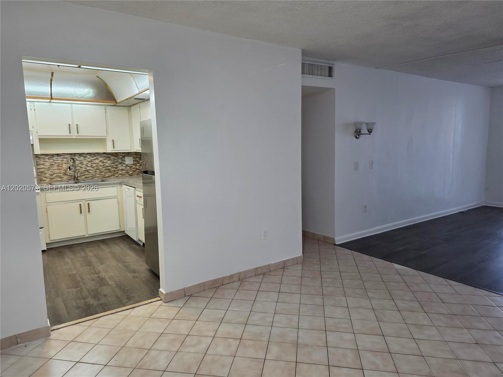A kitchen with white cabinets and a tiled floor opens into a living area — 14150 SW 84th St # I, Miami FL 33183, MIAMI, FL
