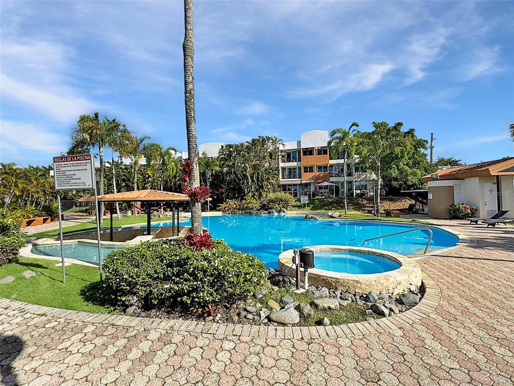A swimming pool and hot tub are surrounded by a stone patio and palm trees — Cond Valles de Torrimar BLVD. PEDRO FULLANA VIRELLA UNIT D-212, GUAYNABO, PR