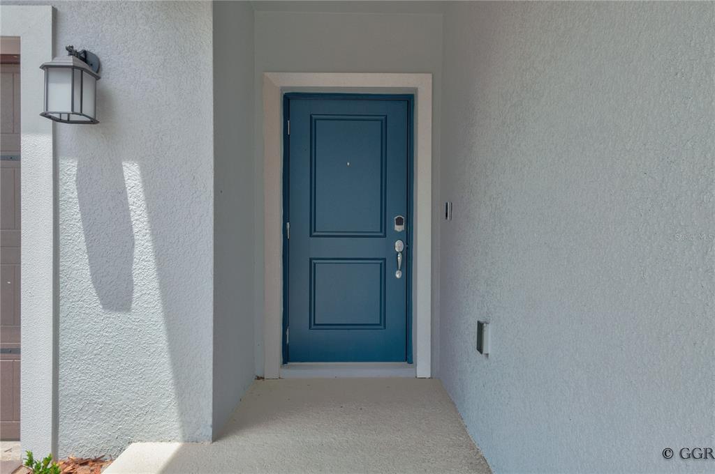A blue front door is set within a recessed entryway with light gray stucco walls — 1490 BRENTWOOD DRIVE, KISSIMMEE, FL