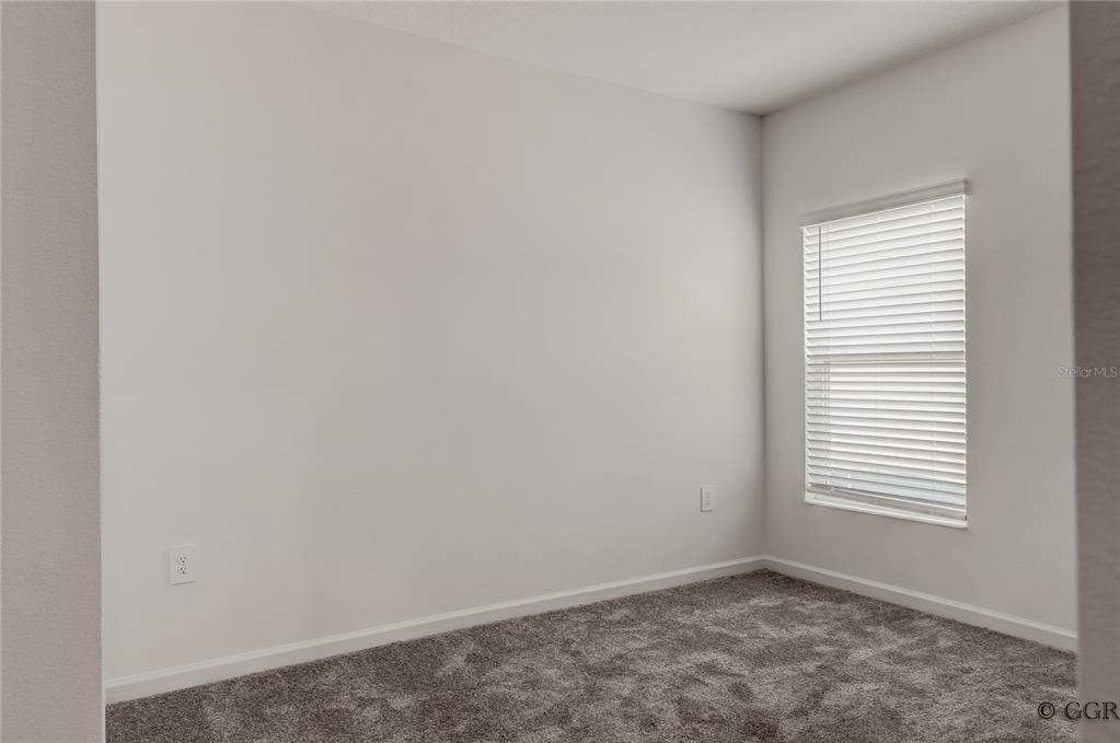 An empty room features gray carpet, white walls, and a window with white blinds — 1490 BRENTWOOD DRIVE, KISSIMMEE, FL