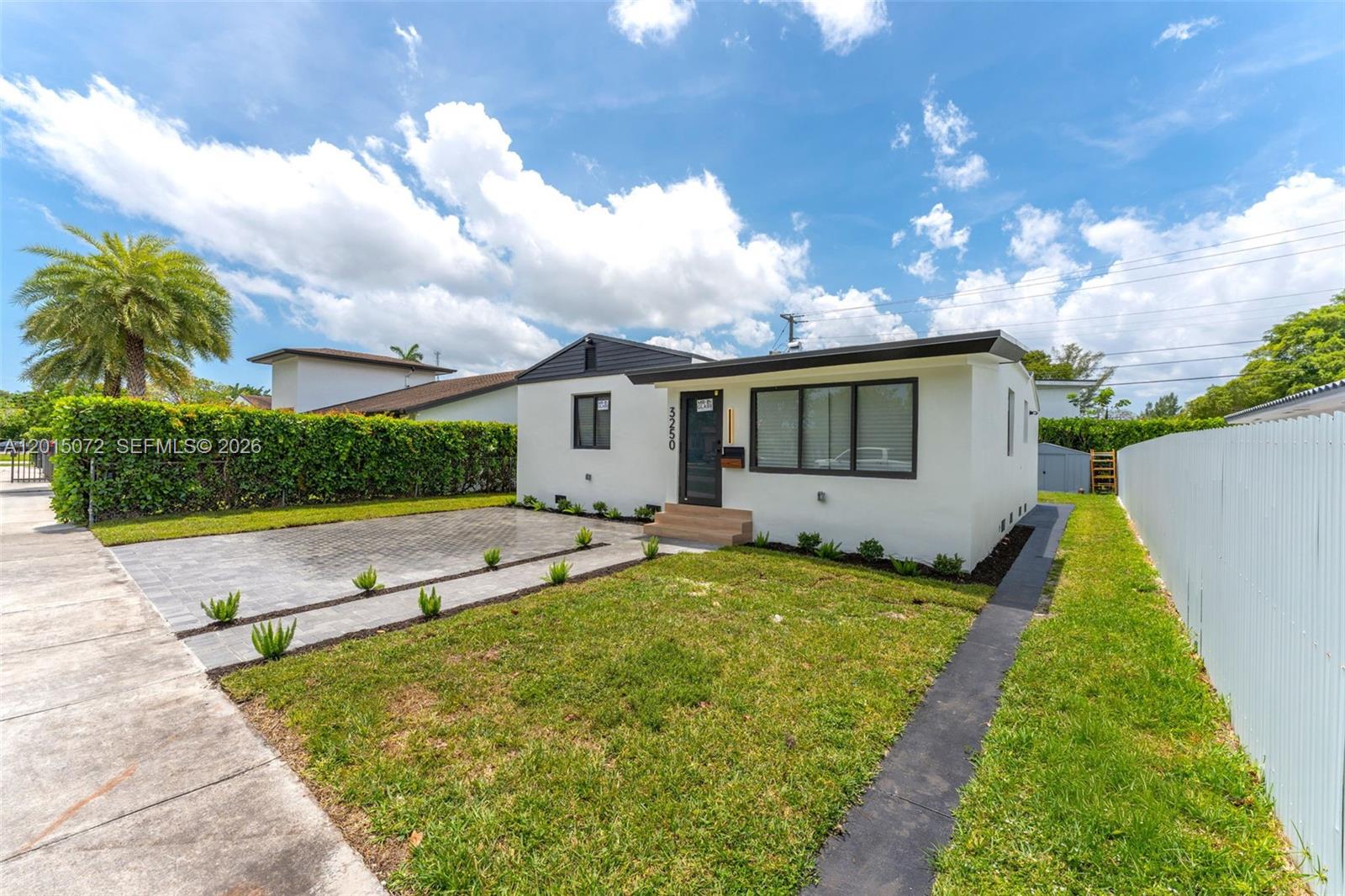 A white single-story house features a paved driveway, a small front lawn, and dark-framed windows — 3250 SW 68th Ave, Miami FL 33155, MIAMI, FL