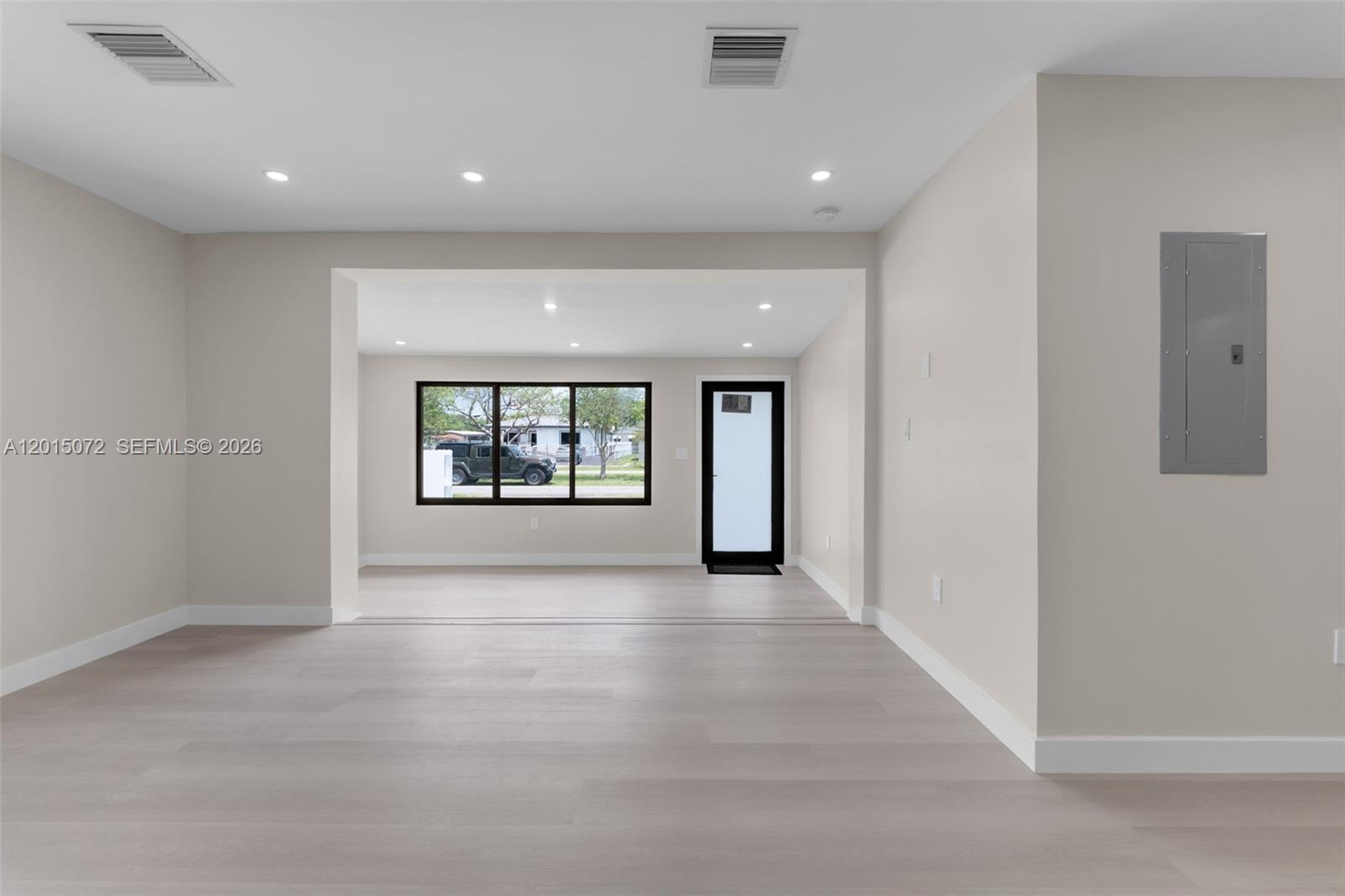 An empty room features light-colored wood flooring, recessed lighting, a window, and a glass door — 3250 SW 68th Ave, Miami FL 33155, MIAMI, FL
