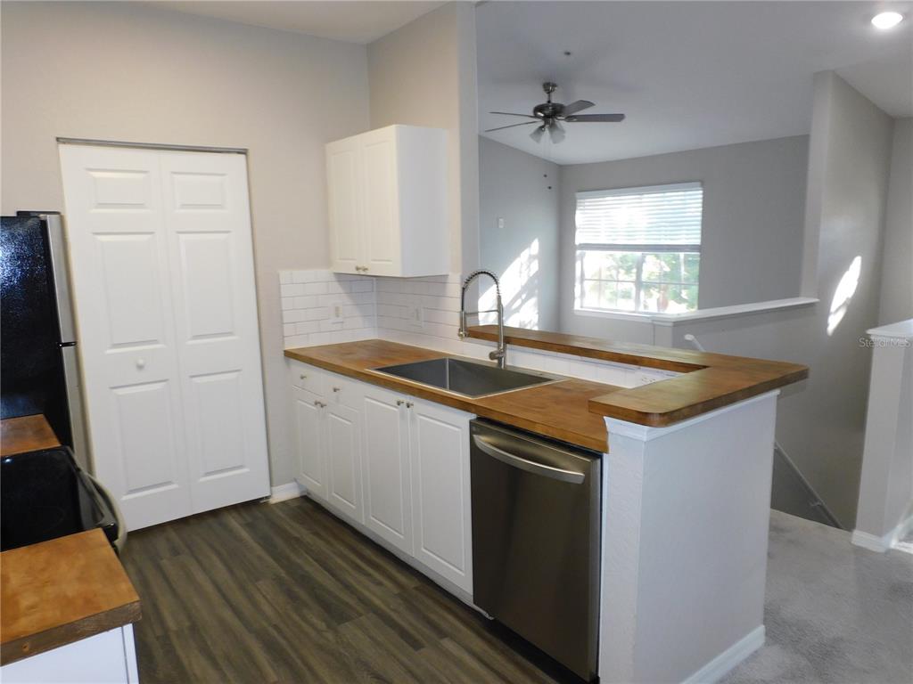 A kitchen features white cabinets, wood countertops, a stainless steel dishwasher, and a sink — 844 GRAND REGENCY POINT UNIT 203, ALTAMONTE SPRINGS, FL