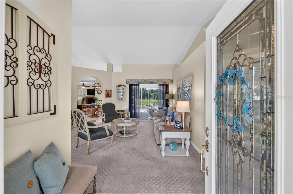 A view from an entryway into a carpeted living room with a sliding glass door — 13857 DEL WEBB BOULEVARD, SUMMERFIELD, FL