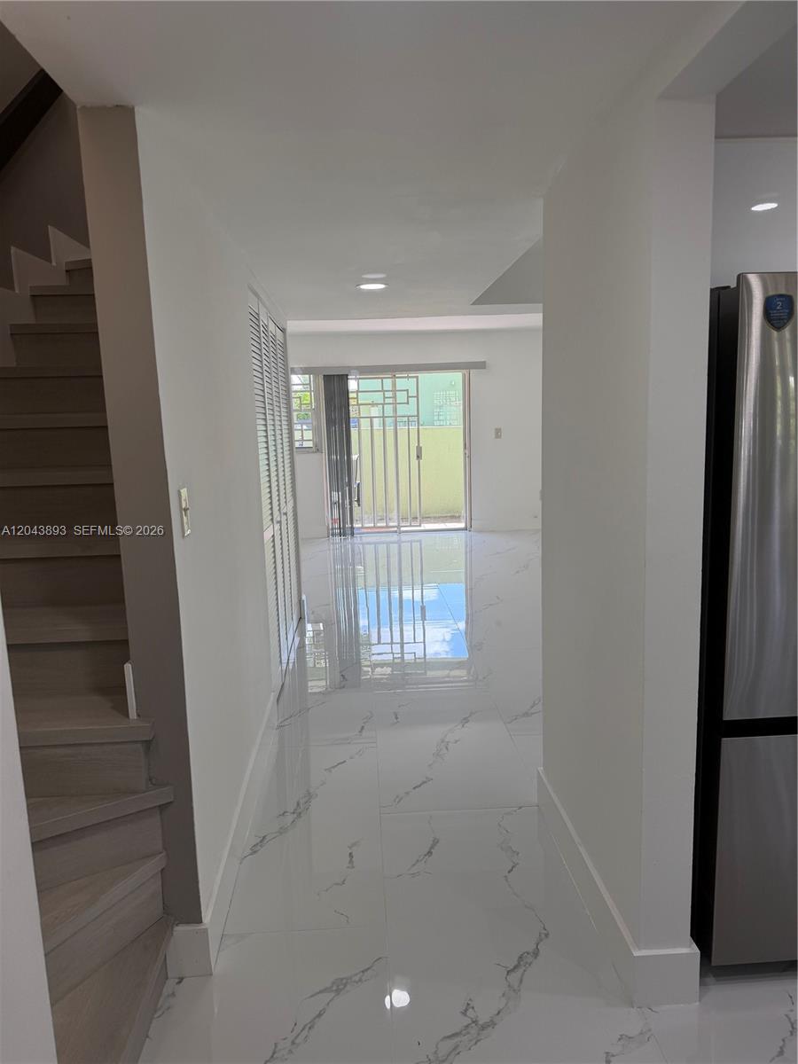 A hallway with white marble-look tile floors leads to a sliding glass door — 11123 NW 7th St # 4, Miami FL 33172, MIAMI, FL