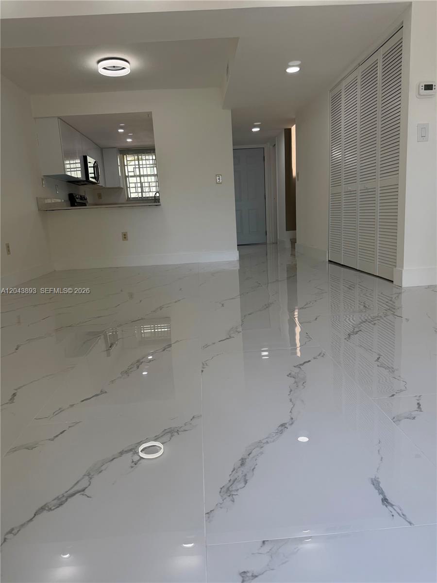 A living area features white marble-look tile flooring, a kitchen pass-through, and white louvered doors — 11123 NW 7th St # 4, Miami FL 33172, MIAMI, FL