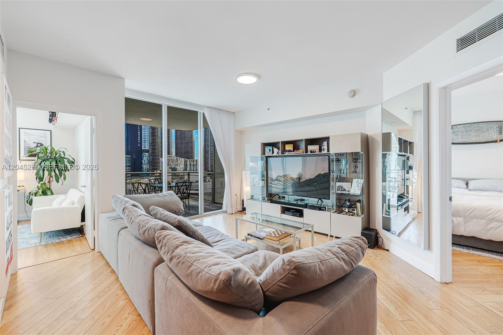 A living room features a large sectional sofa, a media console, and a balcony view — 350 S Miami Ave # 2104, Miami FL 33130, MIAMI, FL