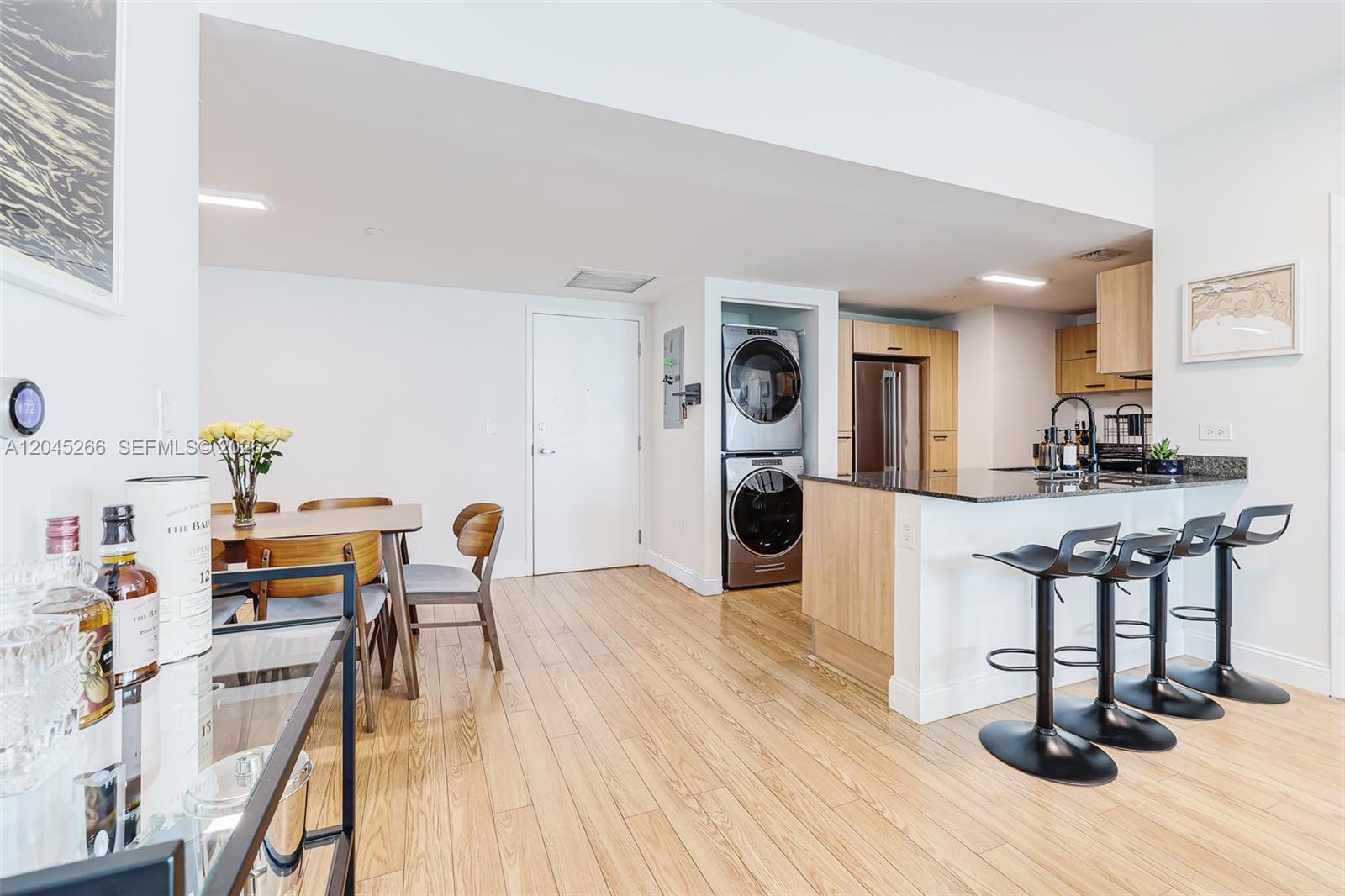 An open-concept kitchen and dining area features light wood flooring, a breakfast bar, and laundry — 350 S Miami Ave # 2104, Miami FL 33130, MIAMI, FL