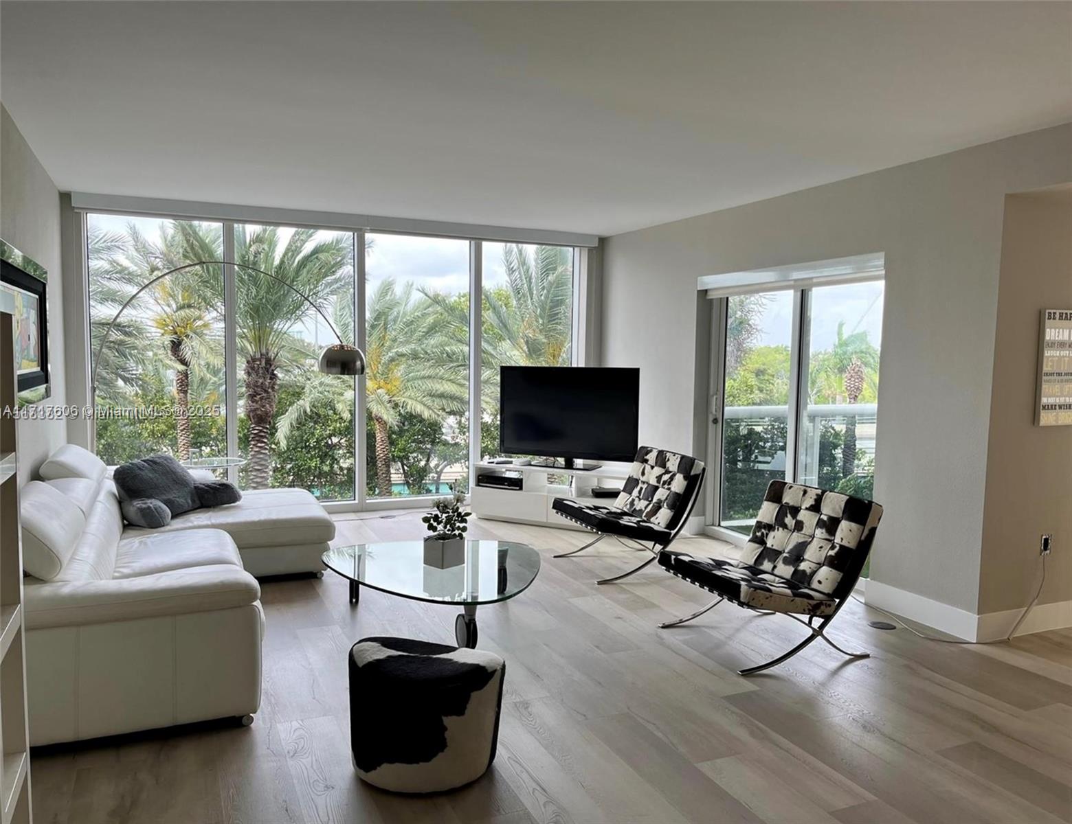 A modern living room features a white sectional sofa, cowhide chairs, and floor-to-ceiling windows — 10275 Collins Ave # 331, Bal Harbour FL 33154, BAL HARBOUR, FL