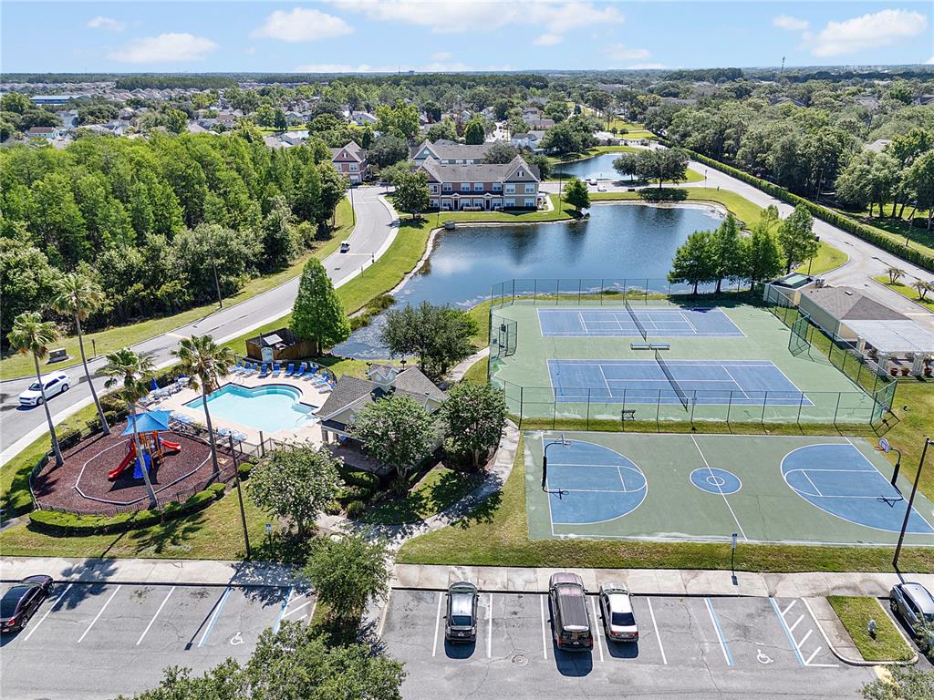 An aerial view shows a community swimming pool and wooden deck overlooking a small lake — 4007 VENETIAN BAY DRIVE UNIT 105, KISSIMMEE, FL