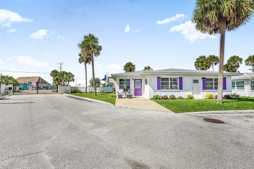 A single-story white house with purple shutters and a purple door sits beside palm trees — 1 PEARL STREET UNIT 1, ENGLEWOOD, FL