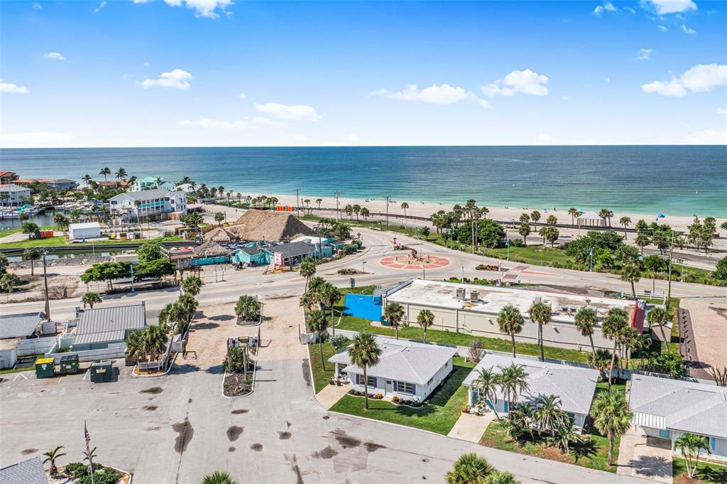 An aerial view shows a coastal area with small houses, a parking lot, and a beach — 1 PEARL STREET UNIT 1, ENGLEWOOD, FL
