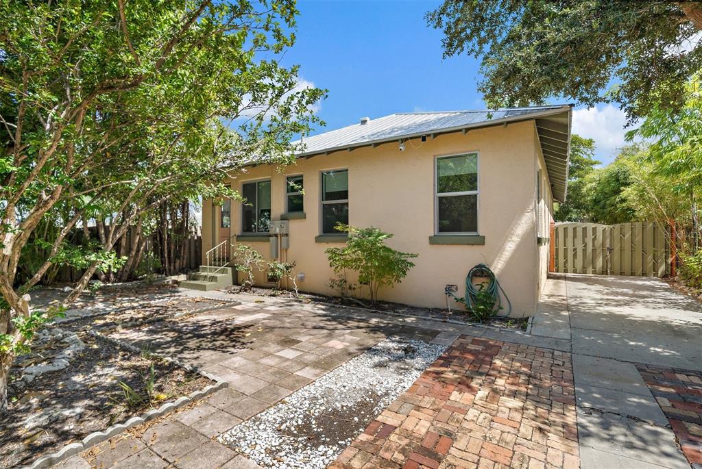 A single-story house with a tan stucco exterior, metal roof, and a brick-paved driveway — 320 OHIO PLACE, SARASOTA, FL