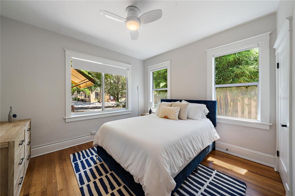 A bedroom features a bed with a blue frame, hardwood floors, and three windows — 320 OHIO PLACE, SARASOTA, FL