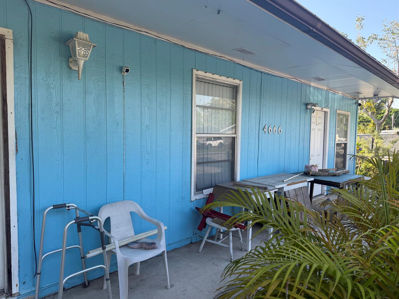 A blue exterior wall features a window, a door, a security camera, and outdoor furniture — 4666 E Holt, West Palm Beach FL 33415, WEST PALM BEACH, FL
