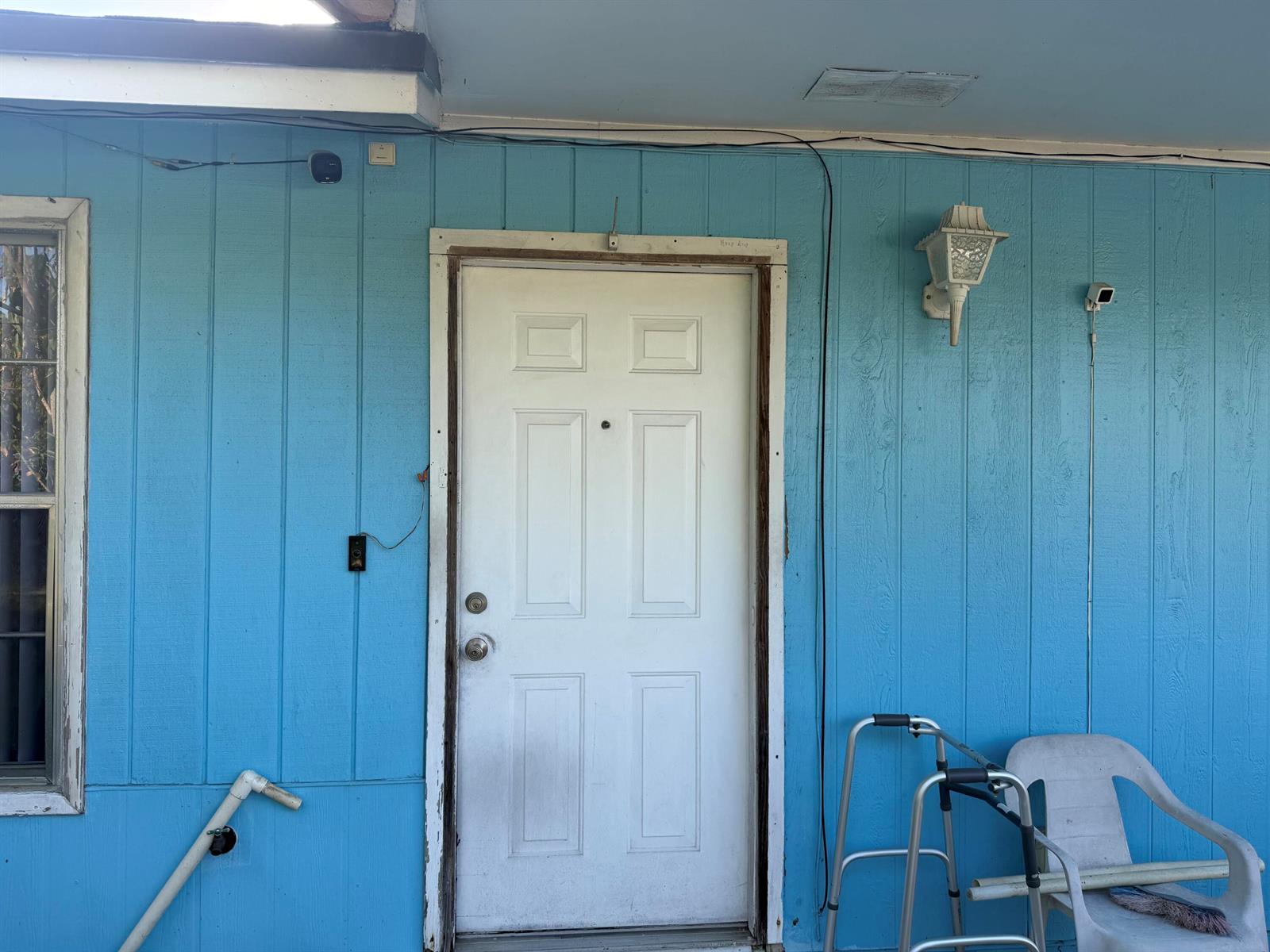A white front door is set in a blue exterior wall with a porch light — 4666 E Holt, West Palm Beach FL 33415, WEST PALM BEACH, FL