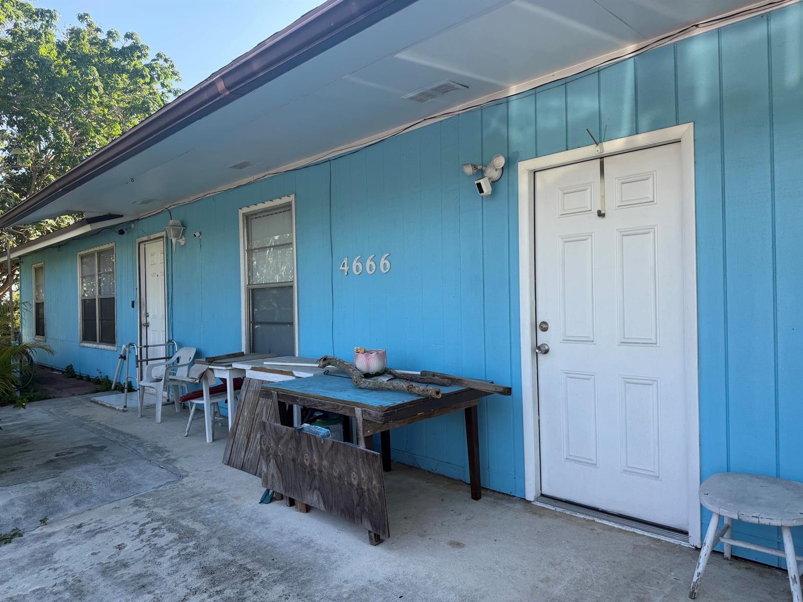 A blue exterior wall features two white doors, two windows, and a table with debris — 4666 E Holt, West Palm Beach FL 33415, WEST PALM BEACH, FL