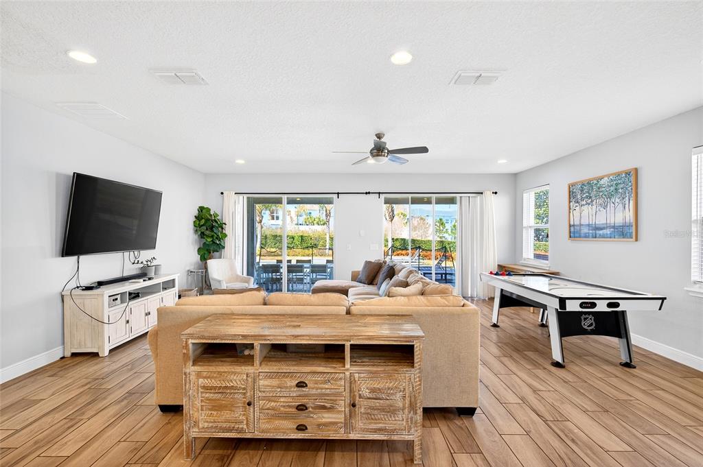 A living room features a tan sectional sofa, a wooden console table, and an air hockey table — 7724 FAIRFAX DRIVE, KISSIMMEE, FL