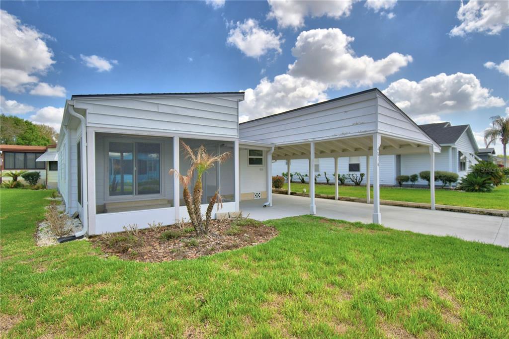 A white manufactured home with a screened-in porch and an attached carport on a lawn — 4816 GOLDENVIEW LANE, LAKELAND, FL