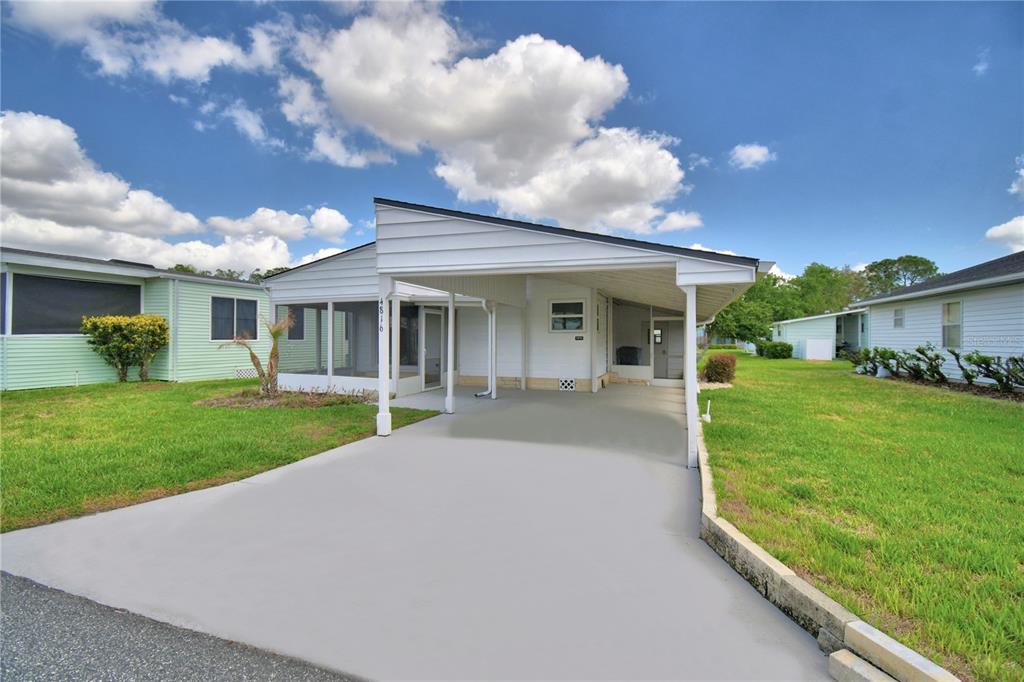 A white mobile home features a concrete driveway, a carport, and a screened-in porch — 4816 GOLDENVIEW LANE, LAKELAND, FL